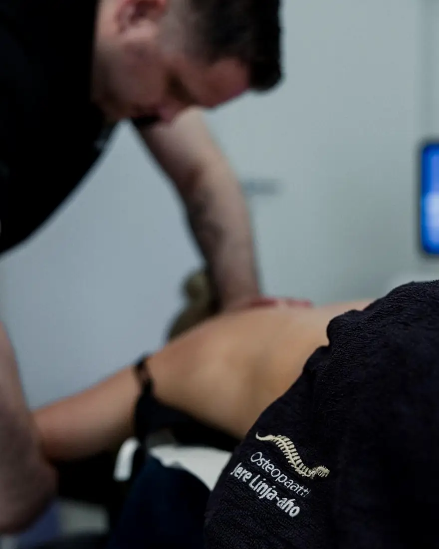 Jere hoitaa asiakkaan selkää. Etualan pyyhkeessä lukee Osteopaatti Jere Linja-aho.